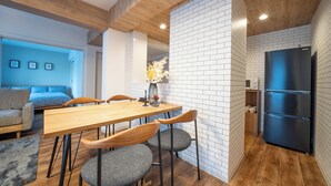 Een moderne keuken met een houten tafel, stoelen en een zwarte koelkast.