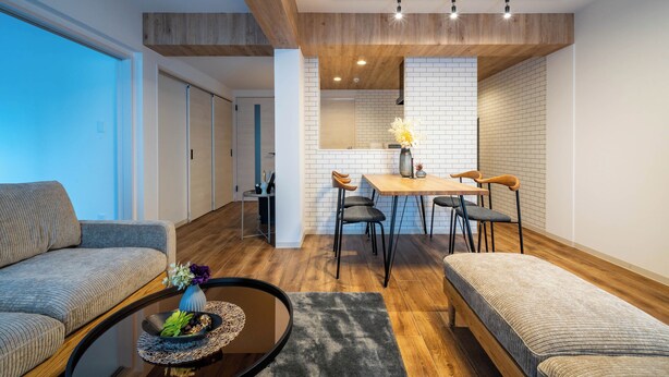 Een moderne woonkamer met een bank, een bijzettafeltje met een vaas en een eethoek met een tafel en stoelen.