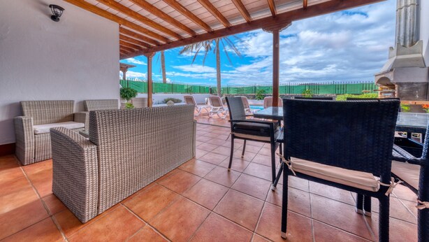 An outdoor patio with wicker furniture, a grill, and a view of the landscape. - Villa Arena Blanca - Pool, Ping-pong and BBQ By LVH (Playa Blanca)