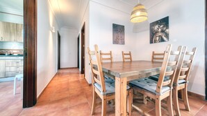 A dining area with a wooden table and chairs, a hanging light fixture, and artwork on the walls. - Villa Arena Blanca - Pool, Ping-pong and BBQ By LVH (Playa Blanca)