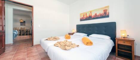 Une chambre d’hôtel avec un grand lit, une table de chevet avec une lampe et un tableau représentant un paysage urbain accroché au mur.
