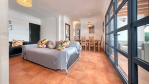 A modern bedroom with a large bed, a dining area, and a view through large windows. - Villa Arena Blanca - Pool, Ping-pong and BBQ By LVH (Playa Blanca)