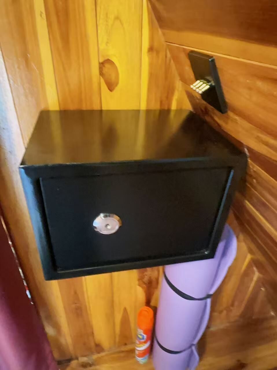 Ein schwarzes Metallwaschbecken mit Wasserhahn, ein violettes Handtuch und eine Seifenflasche in einer Holzhütte.