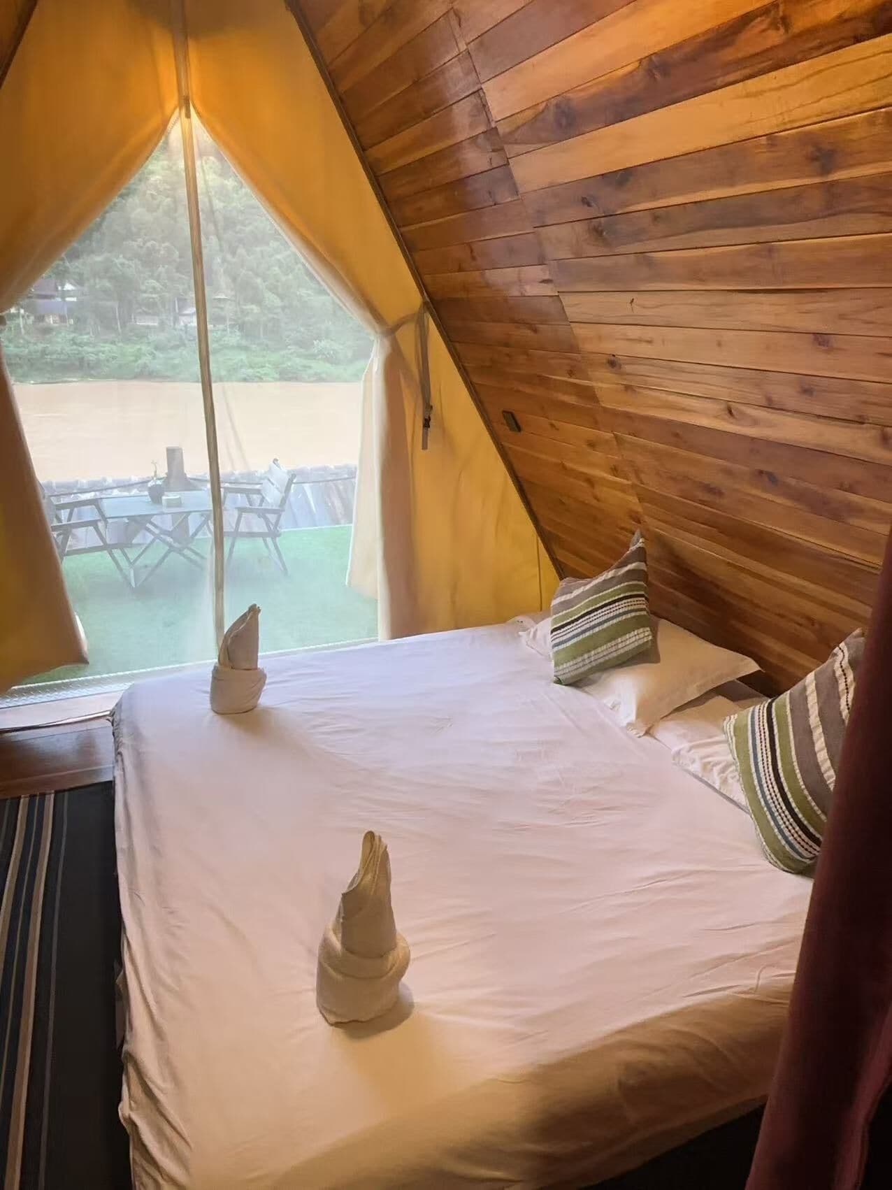 Ein Zelttyp-Zimmer mit Bett, Kissen und Blick ins Freie.
