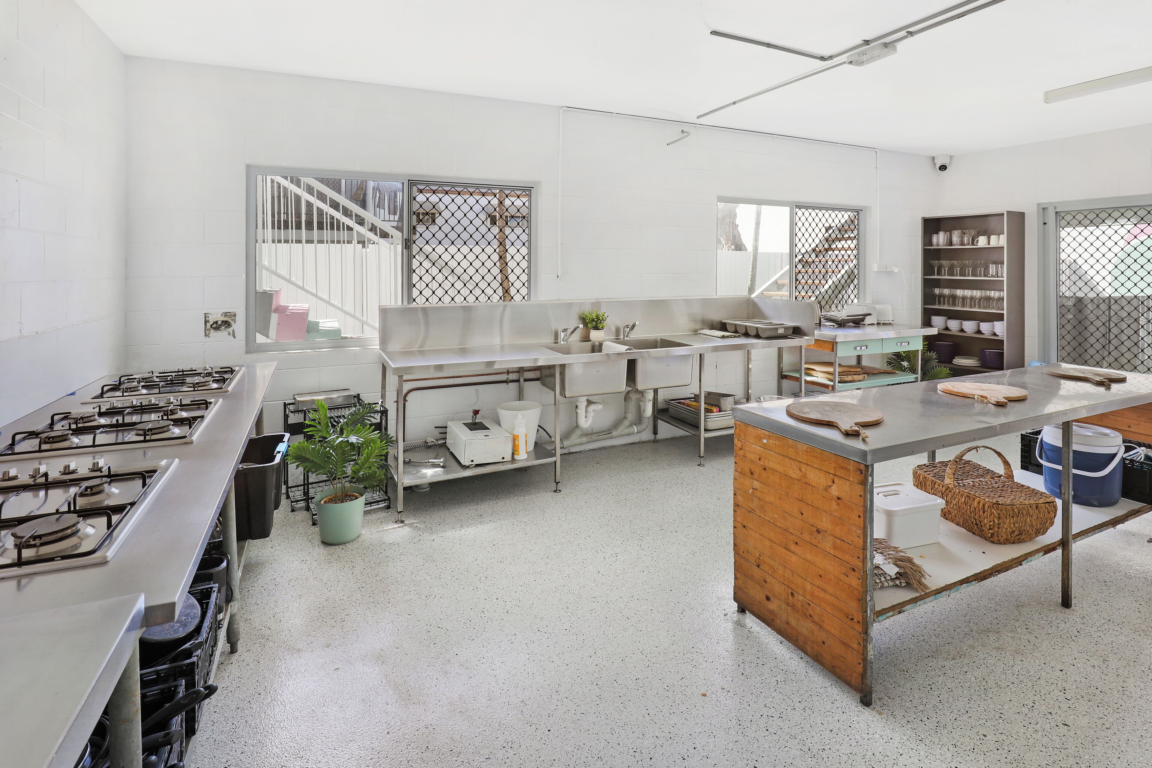A spacious kitchen with stainless steel appliances, a wooden island, and a view of the outside through large windows.