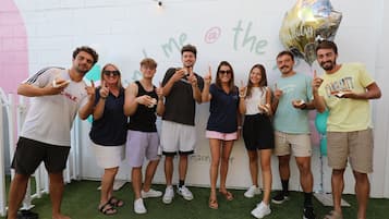 A group of people standing indoors with a white wall and a green artificial turf floor.