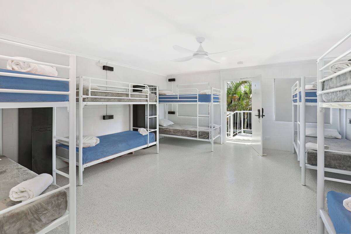 Una habitación con literas, ventilador de techo y puerta que da al exterior.