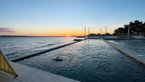 A swimming pool with a sunset view, a lifeguard stand, and a fence. - The Beach Calatagan Mediterraneo powered by Cocotel (Calatagan)