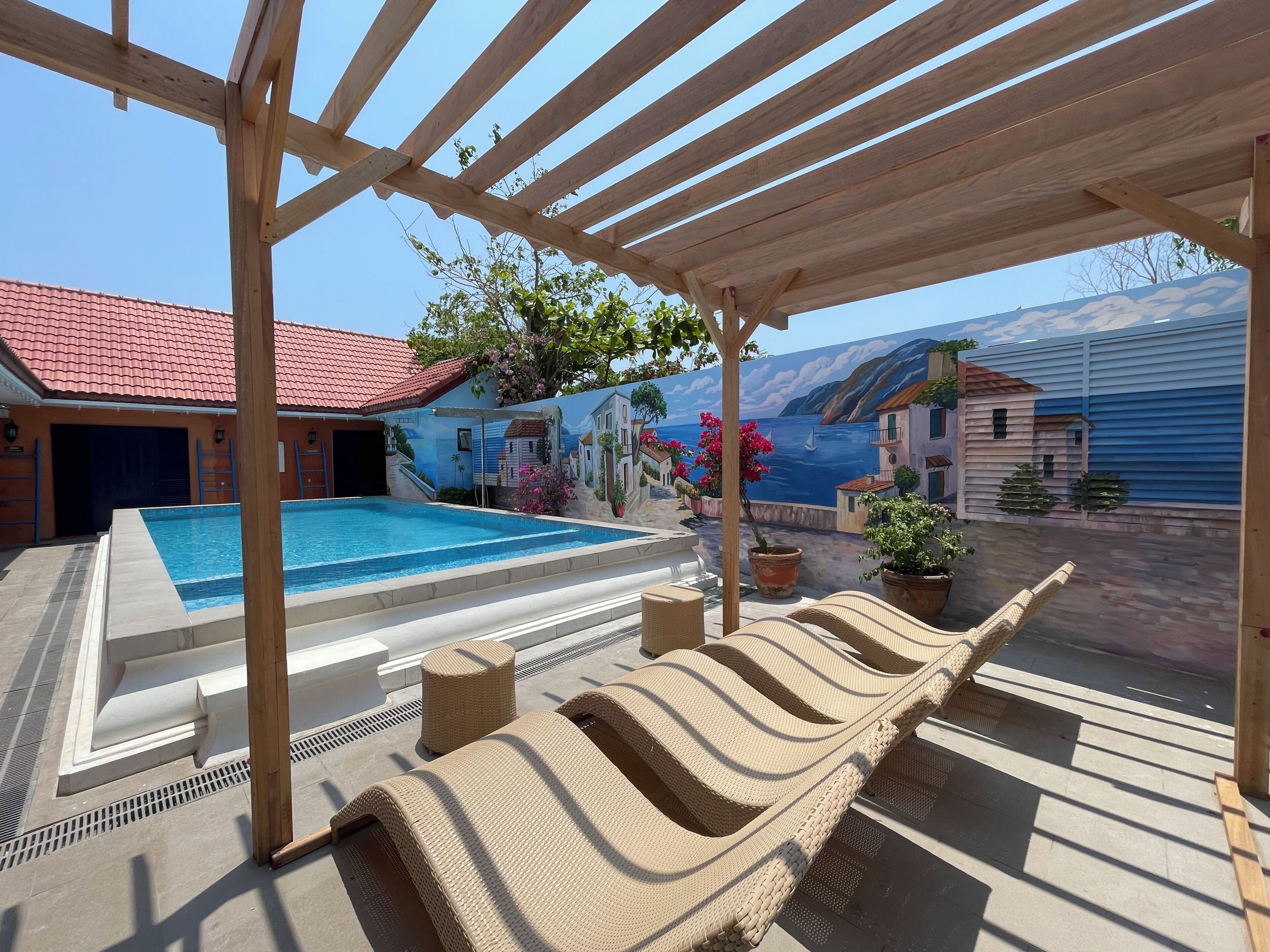 Una piscina cubierta al aire libre con sillones de descanso y plantas en macetas.
