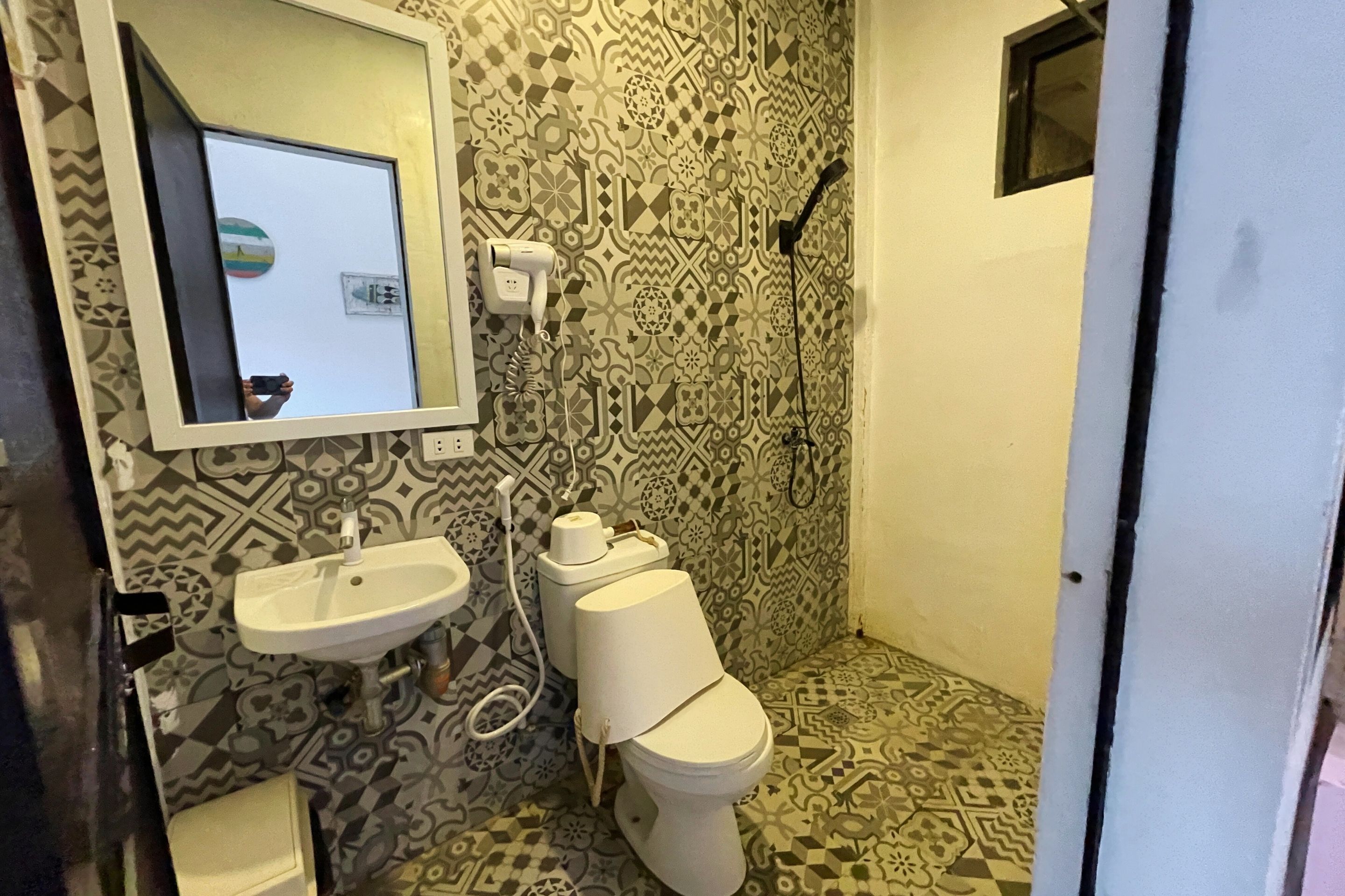 Ein Badezimmer mit Wandmustern, einem Waschbecken, einer Toilette und einem Spiegel.