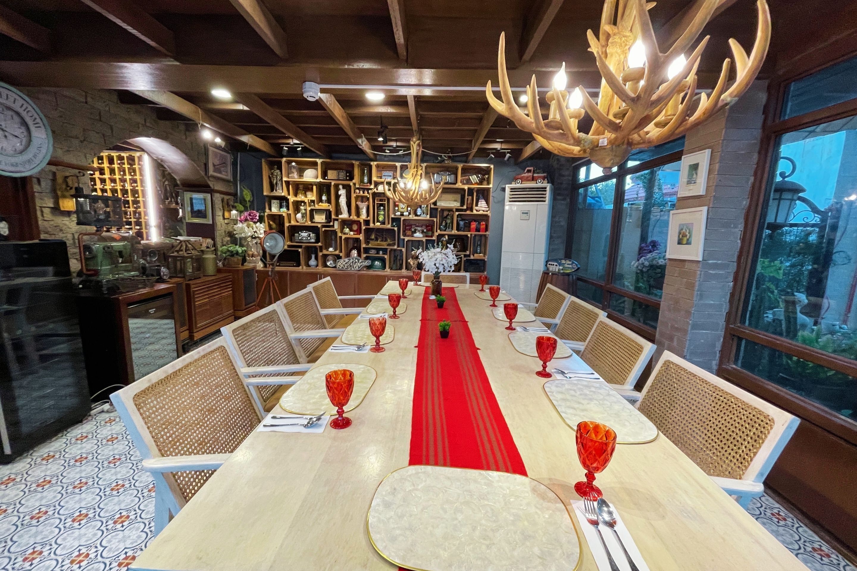 A restaurant with a long table set for a meal, surrounded by chairs, and a red runner down the center.