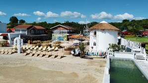 A beachside area with lounge chairs, a small boat, and a water feature. - The Beach Calatagan Mediterraneo powered by Cocotel (Calatagan)