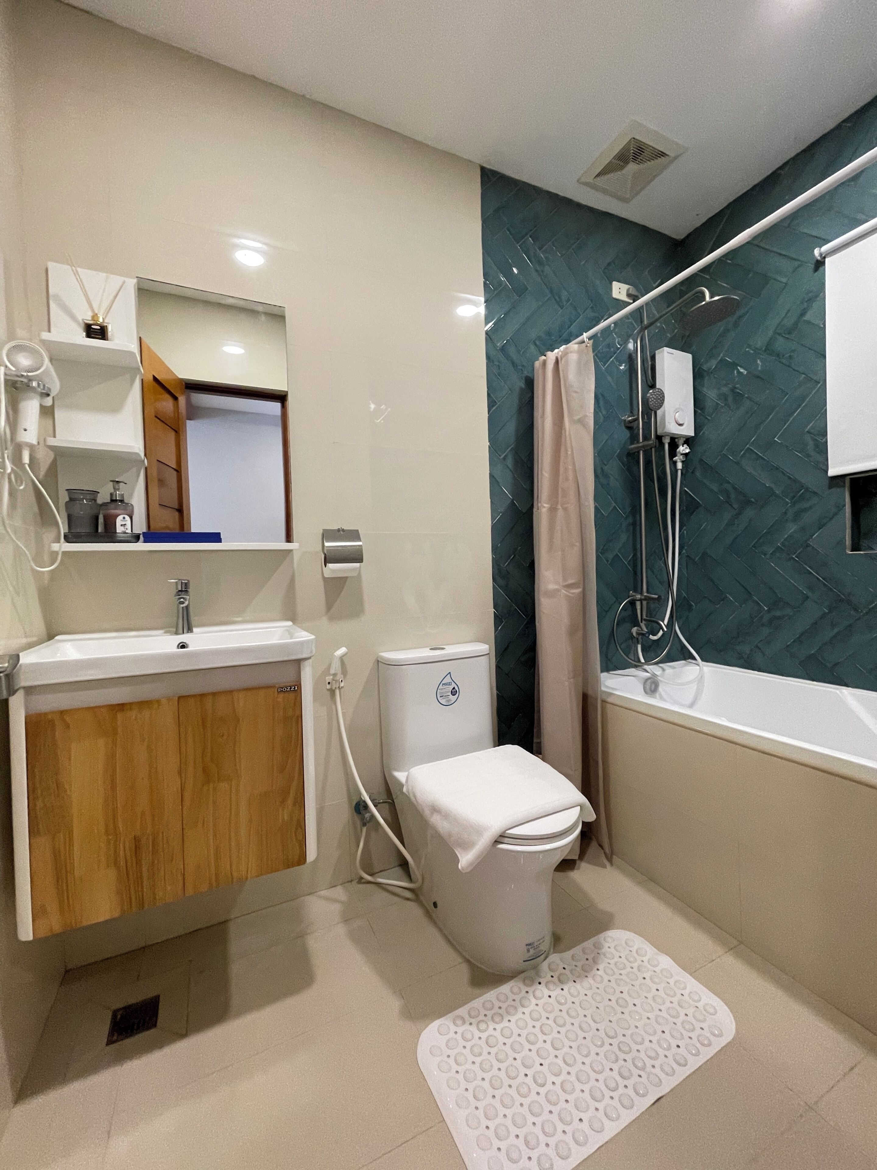 A bathroom with a sink, toilet, shower, and a mirror.