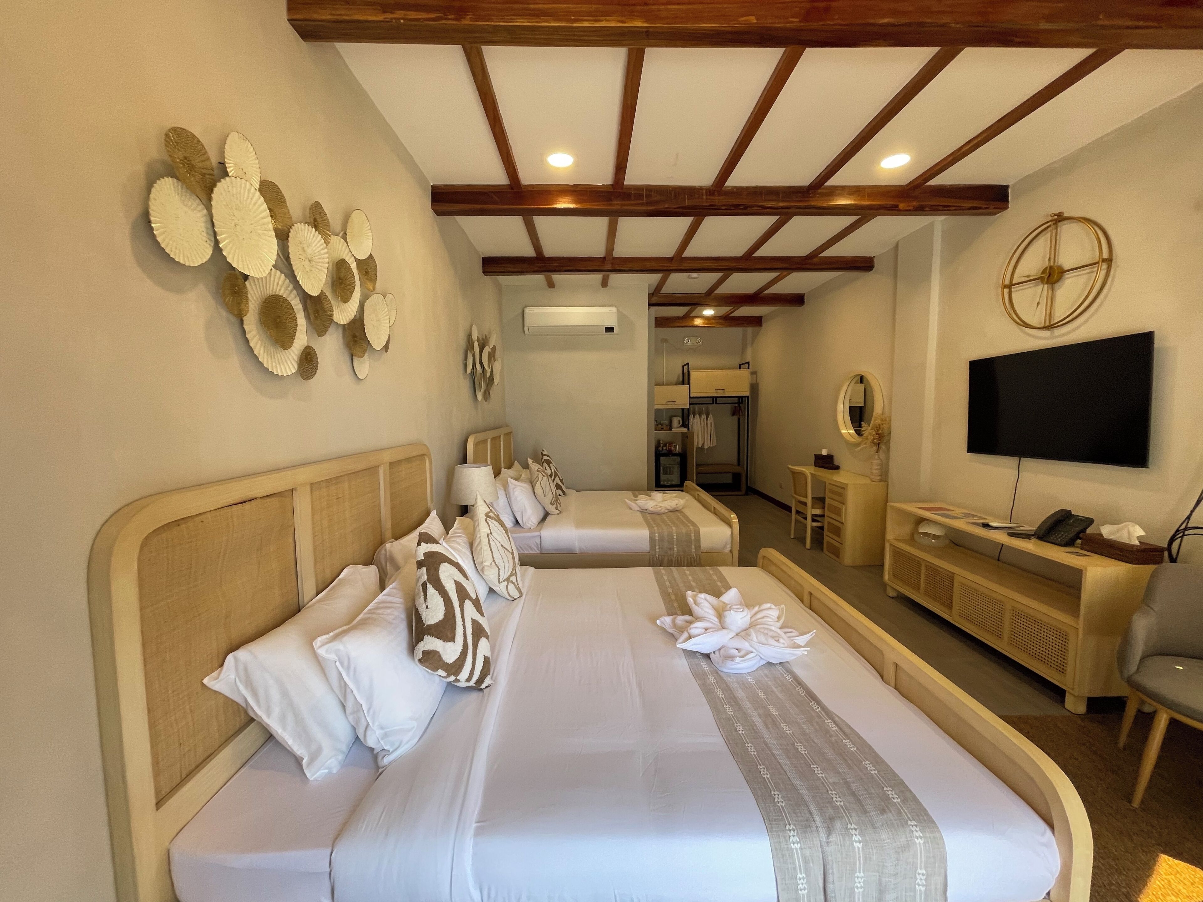 A hotel room with two beds, a desk, a television, and a mirror.