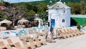 A beachside resort with sun loungers, umbrellas, and a windmill structure. - The Beach Calatagan Mediterraneo powered by Cocotel (Calatagan)