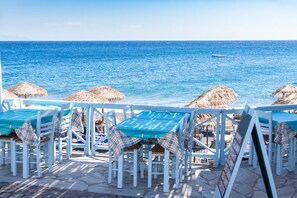 A seaside restaurant with outdoor seating, thatched umbrellas, and a view of the ocean. - Luxus Villa Don Carlos - Playa de Las Américas (Playa de Las Americas)