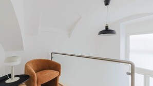 A modern room with a brown chair, a desk with a lamp, and a black pendant light. - Blueground | Leopoldstadt, furniture & decor (Vienna)