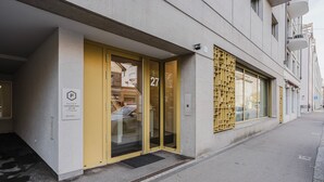 En byggnad med en gul dörr och en entré av glas, märkt med nummer 27.