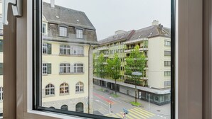 Une vue depuis une fenêtre d’un immeuble à plusieurs étages, doté de balcons, donnant sur une rue avec une piste cyclable.