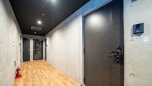 A hallway with a wooden floor, a fire extinguisher, and a door with a security lock. - ZABO HILLS 305 (Sapporo)