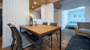 A modern living room with a wooden dining table, chairs, and a sofa. - ZABO HILLS 305 (Sapporo)