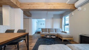 A modern living room with a wooden dining table, sofa, and a black rug. - ZABO HILLS 305 (Sapporo)