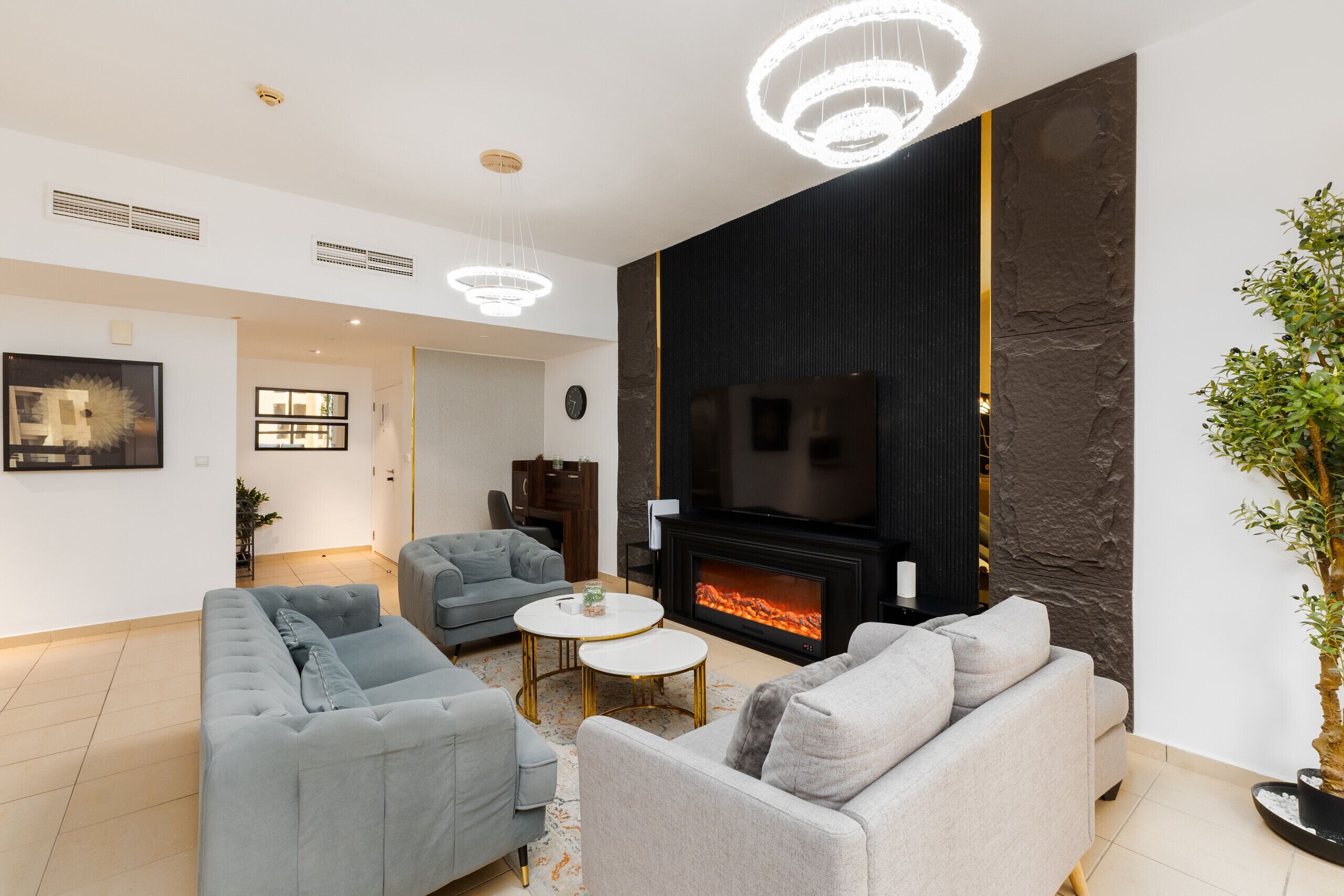 Ein modernes Wohnzimmer mit Kamin, grauen Sofas und einem Flachbildfernseher.