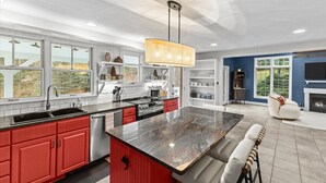 A modern kitchen with red cabinets, a large island, and a view of the outdoors. - Stowe Valley Haven - Beautiful redesigned 4BR home (Stowe)