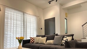 Una sala de estar moderna con un sofá gris, una mesa de centro blanca y un florero con flores.