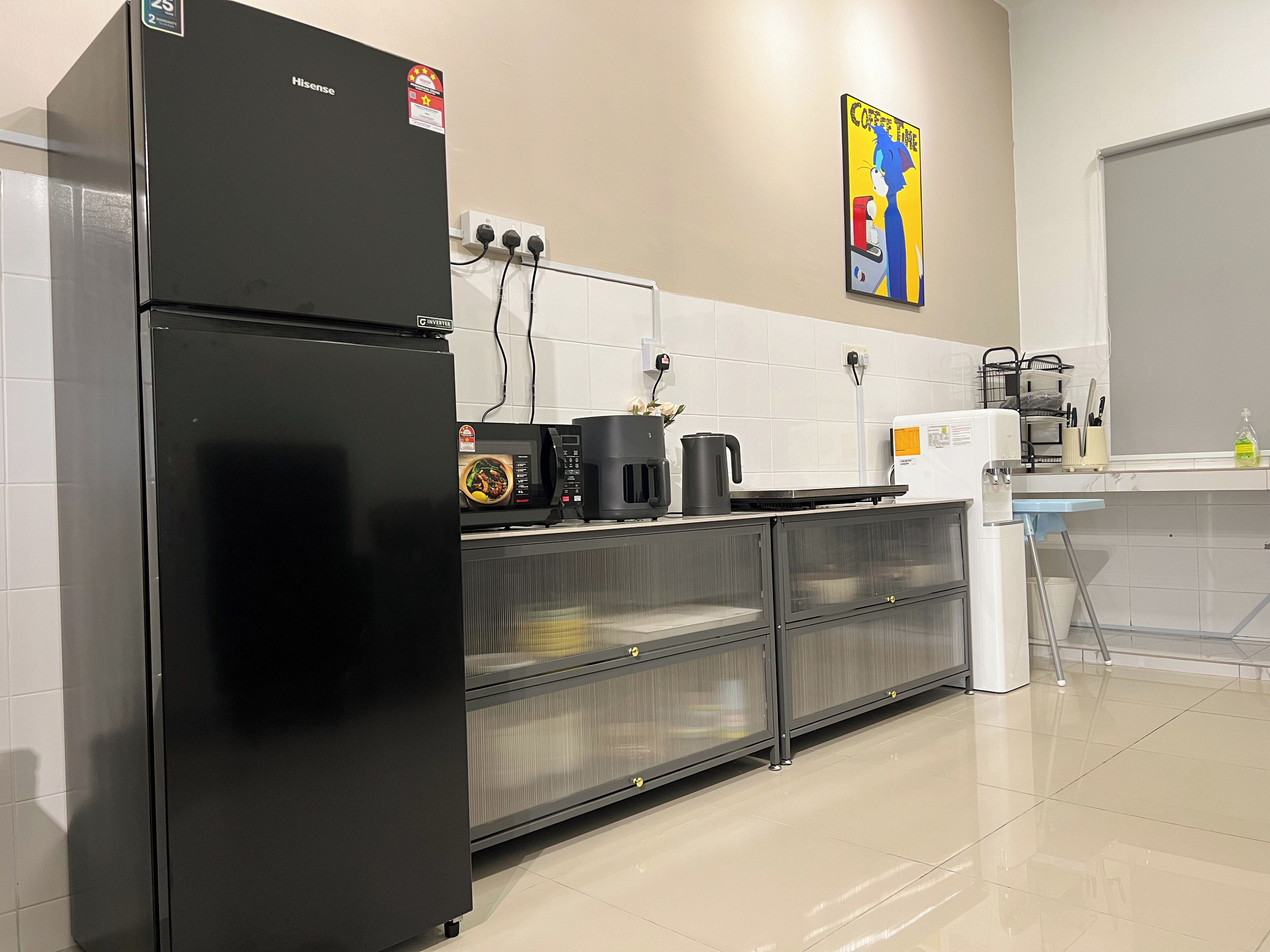 A modern kitchen with a black refrigerator, a microwave, and a coffee machine.