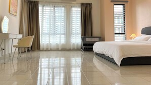 Una habitación de hotel con cama, escritorio con silla, tocador con espejo y ventana con cortinas.