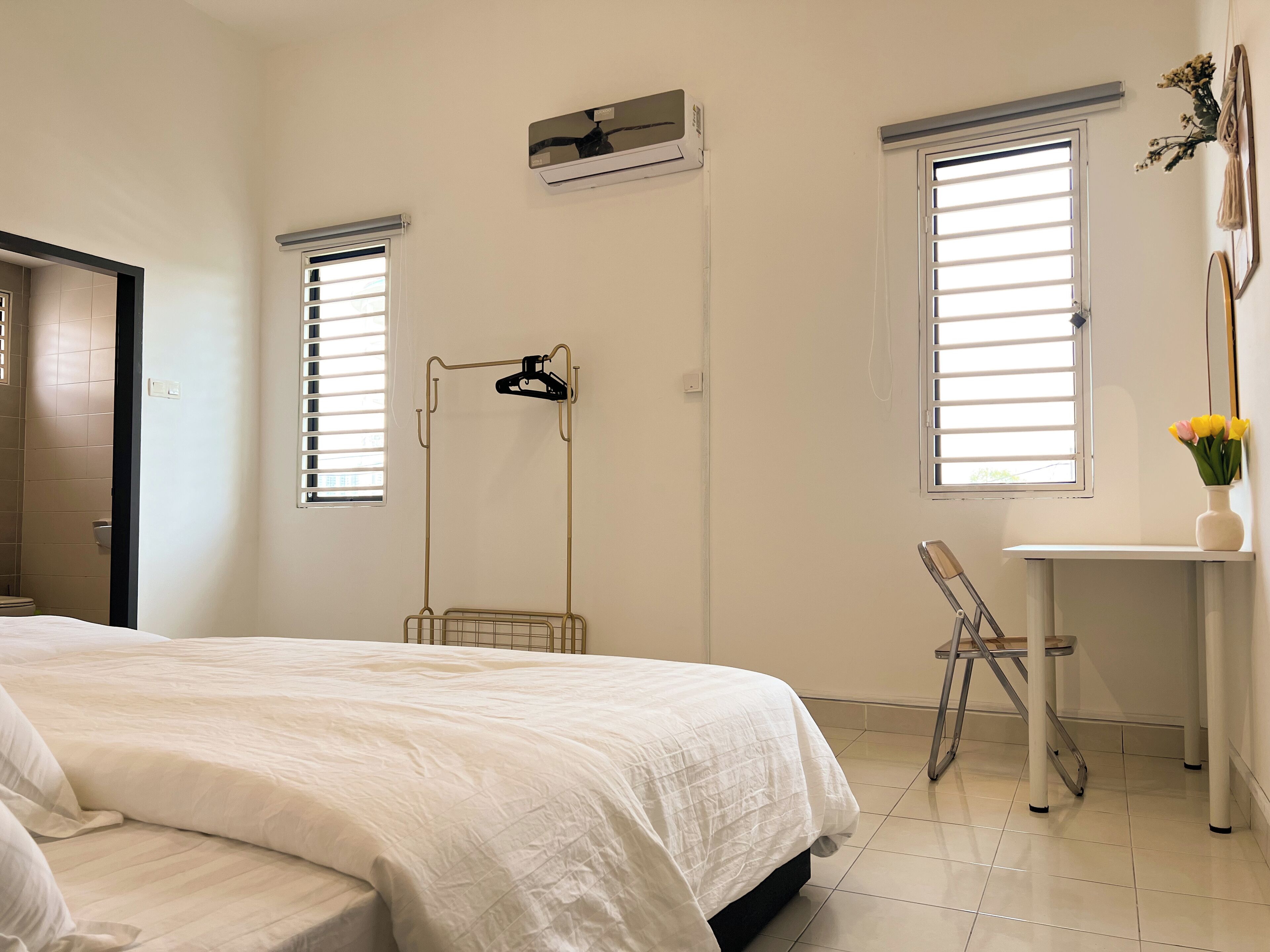 Un dormitorio con cama, escritorio y dos ventanas con persianas.
