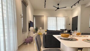 Una sala de estar moderna con comedor, que incluye un sofá, una mesa de centro y un televisor montado en la pared.