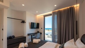 Et moderne hotelværelse med seng, skrivebord, fjernsyn og balkon med udsigt.