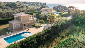 Een villa in mediterrane stijl met een zwembad, meerdere gebouwen en weelderig groen.