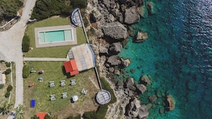 An aerial view of a coastal property with a swimming pool, tennis court, and a gazebo. - Villa Artemis Periyali (Zakynthos)