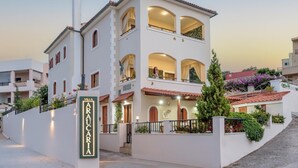 Kerrostalotyylinen huvila, jossa on parveke, ja sen yläpuolella on kyltti, jossa lukee ”VILLA ARAUCARIA”, sekä hyvin hoidettu puutarha.
