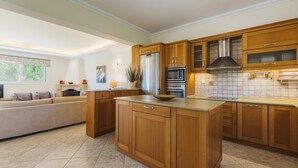 A modern kitchen with wooden cabinets, a central island, stainless steel appliances, and a tiled backsplash. - Villa Lilly with private pool (Zakynthos)