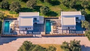 En modern villa med två separata pooler, var och en med solstolar och ett litet bubbelbad.