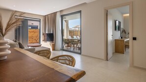 Una sala de estar moderna con una mesa de comedor de madera, sillas de mimbre, un televisor y un ventanal corredizo que da a un balcón con mobiliario exterior.