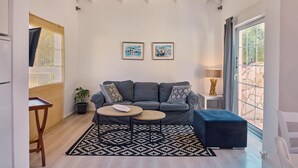 Una sala de estar moderna con un sofá gris, dos mesas redondas de centro, un tapete estampado y dos cuadros en la pared.