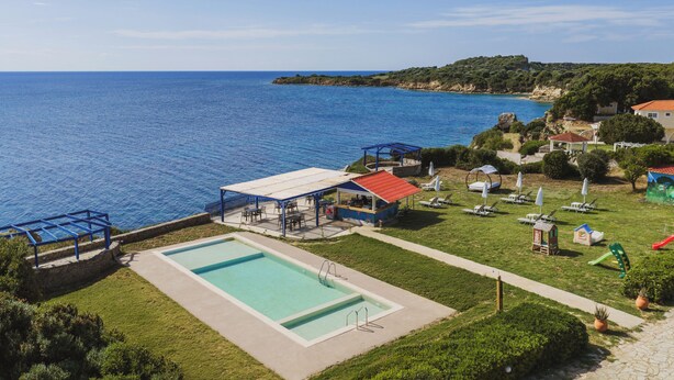 Una piscina, asientos exteriores y vista al mar.