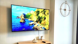 A flat-screen TV mounted on a wall above a wooden entertainment unit with a remote and decorative item on it.