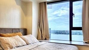 A bedroom with a large bed, a view of the city through a window, and a modern design.