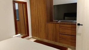 A bedroom with a wooden wardrobe, a bed, and a TV. - Beautiful 1 Bedroom Aldea Zama en Tulum (Tulum)