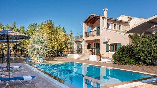 Eine zweistöckige Villa mit Swimmingpool, Sitzgelegenheiten im Freien und einem Garten.