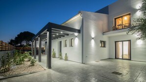 Une maison moderne dotée d’un patio couvert, d’une grande fenêtre offrant une belle vue et d’une entrée bien éclairée.