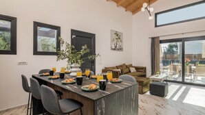 Une cuisine moderne dotée d’un îlot central, de tabourets de bar et d’une table à manger où sont servis des plats pour le petit-déjeuner.