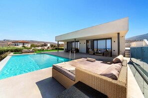 Una villa moderna con piscina, area salotto esterna e vista sul paesaggio.