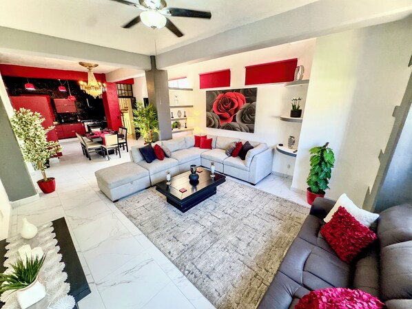 A modern living room with a sectional sofa, a coffee table, and a dining area in the background.